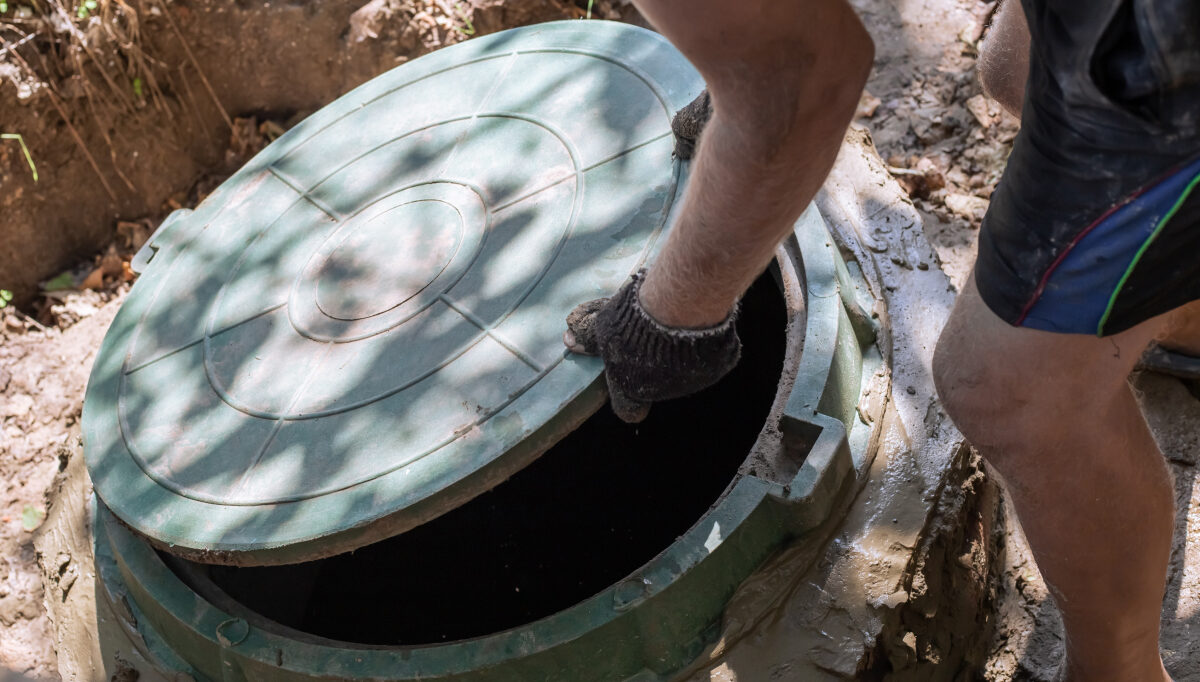Person opening a septic tank lid